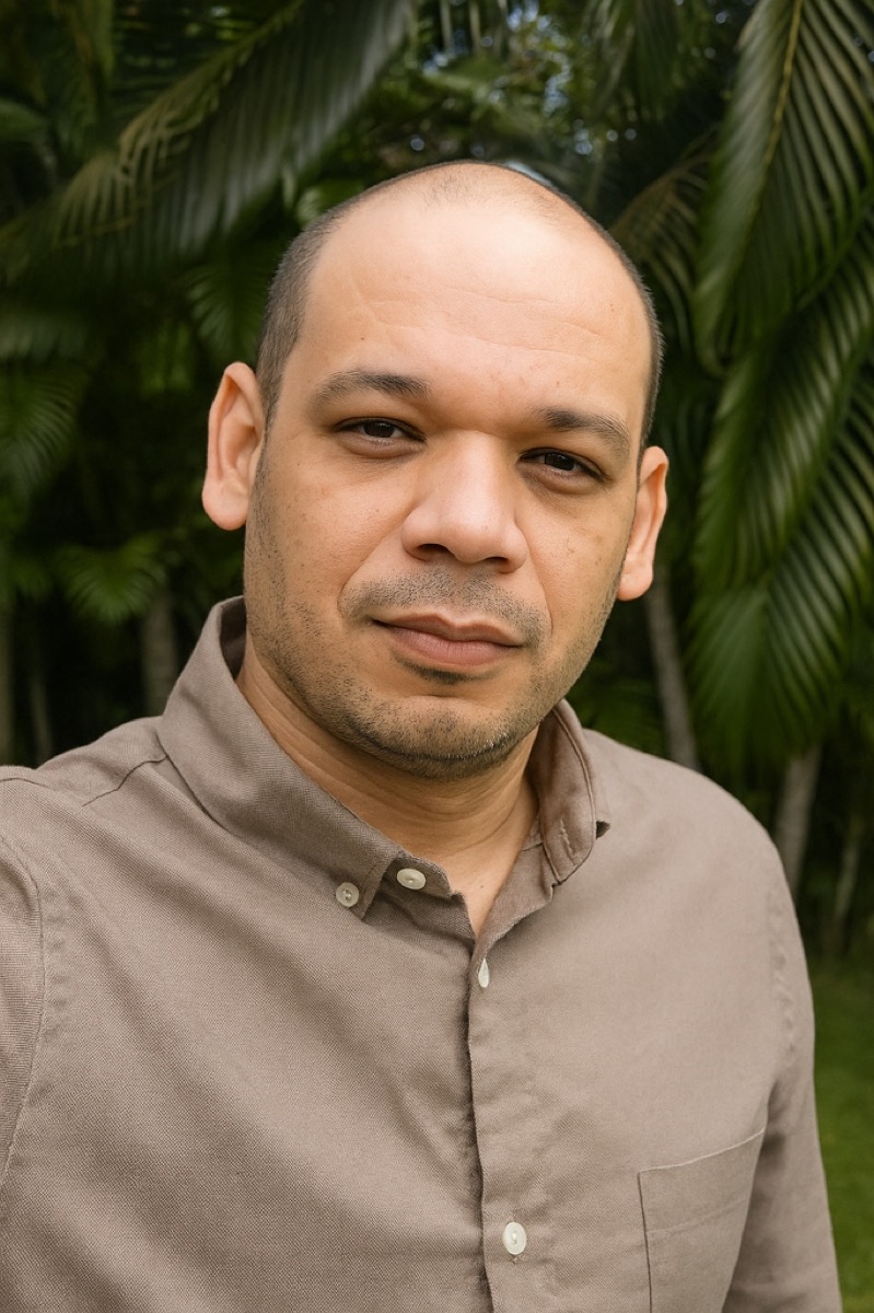 Wellington Brito, psicólogo clínico de orientação psicanalítica, sorrindo com serenidade em meio a folhagens